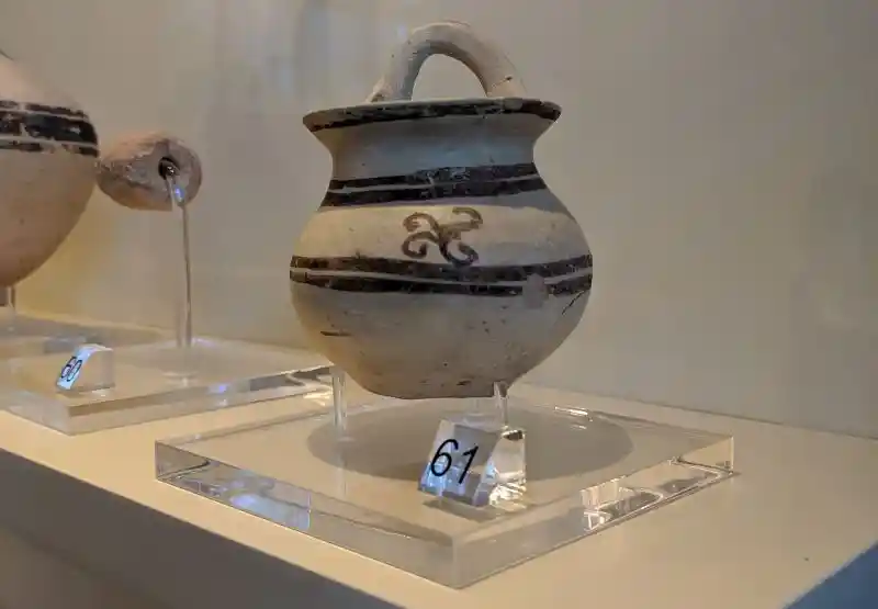Small ancient Greek pottery vessel decorated with painted bands and stylized motif